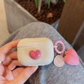 Detail of cream AirPods case featuring pink 3D heart and smiling metal charm accessory - Apricot With Rose Red Heart Charm / AirPods 1/2 Gen