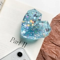 Detail of light blue heart resin phone grip with sparkling sequins on a book - Light Blue