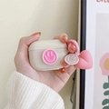 Dettaglio della custodia AirPods beige con faccina rosa 3D e ciondolo a cuore - AirPods 1ª/2ª generazione / Albicocca Faccina Rosa (con Ciondolo a Cuore)