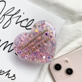Nahaufnahme der herzförmigen Glitzer-Handyhalterung mit Goldtext auf weißem Buch - Glitzer Halterung-Herz Englisch / Rosa