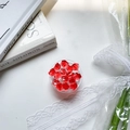 Close-up of red acrylic ice stones in a clear tray on a decorative white table - Red Crushed Ice