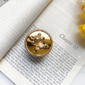 Dettaglio dell'anello supporto telefono con orso 3D dorato su un libro elegante - Supporto ad Anello Oro-Orso Cicciottello-Specchio Oro