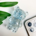 Detail of light blue resin bear phone grip with silver foil flakes on white surface - Transparent Light Blue
