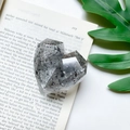 Detailed view of heart-shaped faceted phone grip with black glitter and resin texture - Faceted Heart Stand - Silver Foil - Transparent Grey