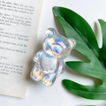 Macro shot of a holographic bear phone grip with white heart detail on a bright background - Bear with Heart / Holographic Silver