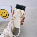 Creamy Galaxy Z Flip heart case featuring a stylish white pearl wrist strap handle - PC-Rendered Heart-Pearl Chain / Samsung ZFlip3