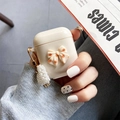 Detalle de funda AirPods crema con lazo de lunares y colgante corazón de perlas - Albaricoque / Pro Gen 2
