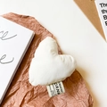 Detail of white fabric heart phone grip with creative label on textured paper background - White