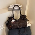 Donkerbruine tote bag van imitatie suède met witte stiksels en een pluche pompon hanger - Met Hanger / koffiekleur