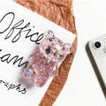 Macro detail of a cute 3D pink glitter bear foldable phone grip on textured paper - Red