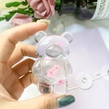 Detail of transparent bear phone grip featuring real pink dried flowers embedded in resin - Pink