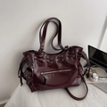 Detailaufnahme der burgunderroten Ledertasche mit Kordelzug, Seitenschnallen und Ösen - Burgunderrot