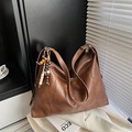 Borsa tote vintage in pelle marrone con nappa di perline e tracolla regolabile su sfondo minimale - Marrone