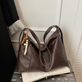 Borsa tote in ecopelle marrone scuro con ciondolo vintage su un libro aperto - Marrone