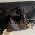 Borsa tote vintage in pelle marrone scuro con tracolla regolabile su biancheria da letto - caffè