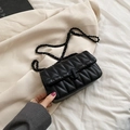 Sac bandoulière matelassé noir avec chaîne et fermoir rond sur fond de blazer élégant - Noir