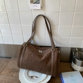 Detail einer dunkelbraunen Wildleder-Schultertasche mit Doppelreißverschluss auf Holz - Braun