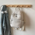 Chic beige lychee textured backpack for women with metal logo on a wooden coat rack - Off-white