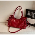Close-up of red patent leather tote bag with functional side drawstrings and pockets - Red
