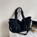 Dettaglio della borsa tote in tela nera con borchie in metallo e tracolla larga sportiva - Nero