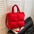Borsa tote trapuntata rosso vivace con manici e tracolla su un divano nero - Rosso