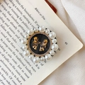 Detail of vintage style circular phone stand with gold bow and pearl border accents - Strapped Bow / Black
