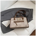 Detailansicht der grauen Vintage-Schultertasche mit braunen Riemen auf einem Blazer - Braun