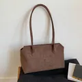 Vista detallada del bolso tote de ante marrón oscuro con correas finas y textura suave - Marrón