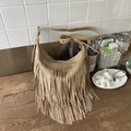 Borsa a spalla in camoscio kaki con frange e nappe su tavolo in legno scuro - Cachi
