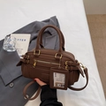 Bolso Boston marrón con asas dobles, herrajes dorados y etiqueta de identificación colgante - Marrón