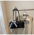 Detail der schwarzen Lackleder-Schultertasche mit weißer Spitzenschleife am Kleiderbügel - Schwarz
