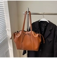 Detalle del bolso tote marrón en piel sintética con lazo decorativo y cordones laterales ajustables - Marrón