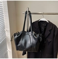 Detalle del bolso tote de cuero negro brillante con cordón y lazo en un soporte - Negro