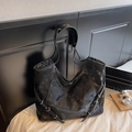 Retro distressed black leather tote bag with silver buckle details on white bedding - Black