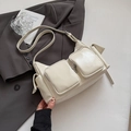 Détail d'un sac bandoulière crème en similicuir avec plusieurs poches brillantes - Blanc