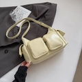 Détail d'un sac à bandoulière jaune crème brillant avec plusieurs poches sur un blazer - Jaune