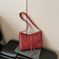 Borsa a secchiello rossa intrecciata con nappe su seduta in pelle nera e libro grigio - Rosso