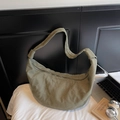 Sac bandoulière croissant vert olive minimaliste avec détails matelassés sur lit - Vert