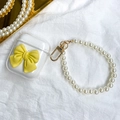 Macro shot of clear AirPods case with yellow bow and pearl lanyard on white silk - Yellow / AirPods 1/2