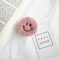 Nahaufnahme der rosa Plüsch-Handyhalterung mit gesticktem Smiley auf Stoffhintergrund - Rot