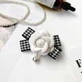 Dettaglio supporto telefono camelia con fiocco pied-de-poule e ciondolo di perla - Supporto Camelia in Pelle a Quadri Bianchi