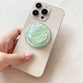 Detail of mint green iridescent shell texture foldable phone grip on a beige smartphone - Threaded Magnetic Stand / Light Green