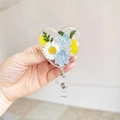 Dettaglio del porta badge a forma di cuore in resina con veri fiori secchi e clip - Stile Foresta Margherita Bianca Blu (1)