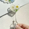 Macro shot of heart-shaped badge reel featuring real dried flowers in clear resin - Glitter White Flower