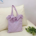 Borsa tote in tela a fiori viola con volant e etichetta Magiopocket su un divano - Rosa