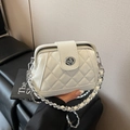 White quilted doctor bag with silver twist lock and chain strap held by a person - White