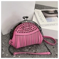 Borsa a tracolla rosa con borchie, frange metalliche e catena su piano materico - Rosa