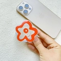 Détail d'un support de téléphone fleur orange minimaliste sur un smartphone doré - Petite Fleur Rouge