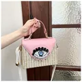 Detalle de solapa de cuero rosa con bordado de ojo y lentejuelas en bolso de paja - Rosa
