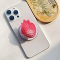 Dettaglio del supporto per telefono a forma di fragola rosa su uno smartphone bianco - Supporto Magnetico / Fragola Neve Chiara